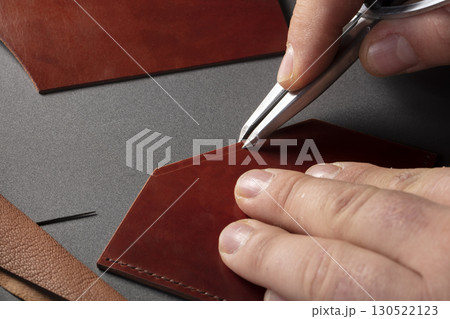 The process of making leather goods. The hands of the master work with a leather product. 130522123