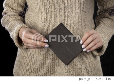 A brown leather wallet is in women's hands. A brown leather wallet is in women's hands. 130522140