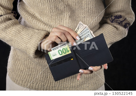 In female hands, a brown wallet with euros and dollars. 130522145