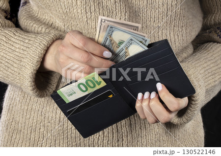 In female hands, a brown wallet with euros and dollars. 130522146