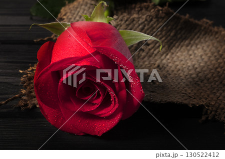 Red rose close-up with water droplets on a wooden background. Beautiful flower. Red rose close-up with water droplets on a wooden background. Beautiful flower. 130522412