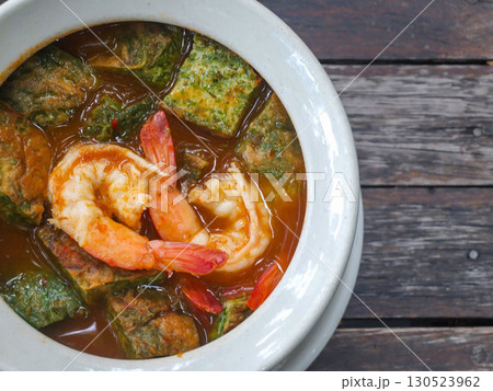 Thai food: Cha-om egg curry with shrimp in a white bowl on a wooden table. 130523962