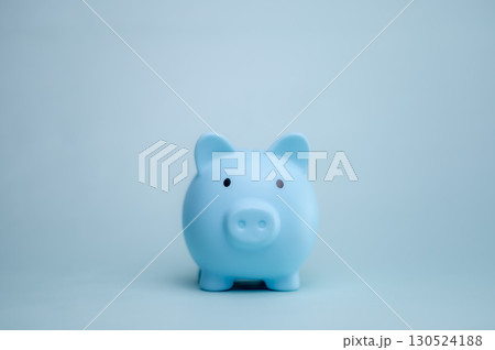 A hand is dropping coins into a piggy bank. The concept of saving and investing. A hand is dropping coins into a piggy bank. The concept of saving and investing. 130524188