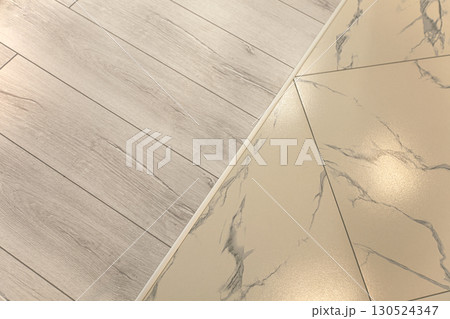 A neat joint between ceramic tiles and laminate flooring. A neat joint between ceramic tiles and laminate flooring. 130524347