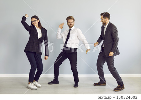 Three business people dancing and celebrate success in business isolated on grey background. Three business people dancing and celebrate success in business isolated on grey background. 130524602