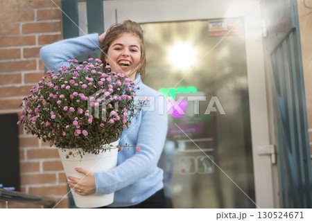 A beautiful girl is holding a large bouquet of flowers and smiling. Happy young woman in the city. A beautiful girl is holding a large bouquet of flowers and smiling. Happy young woman in the city. 130524671