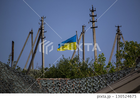 Ukrainian national flag waving in the wind against blue sky and power poles. Symbol of freedom, patriotism, independence and national identity Ukrainian national flag waving in the wind against blue sky and power poles. Symbol of freedom, patriotism, independence and national identity 130524675