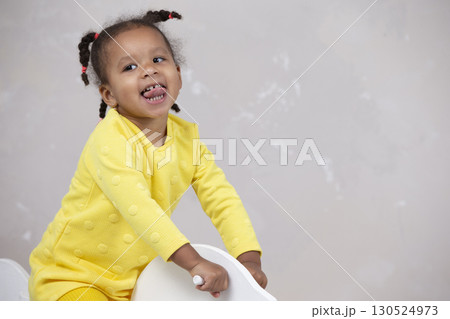 Little African American girl in yellow clothes shows tongue. Funny child. Little African American girl in yellow clothes shows tongue. Funny child. 130524973
