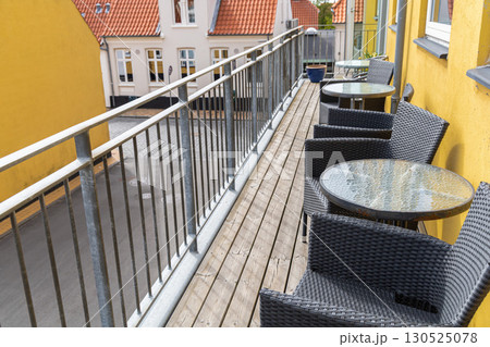 A large veranda or balcony with chairs and tables for relaxing on a summer day. 130525078