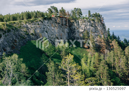 Rocky cliff mountains surrounded by pine forest in summer 130525097