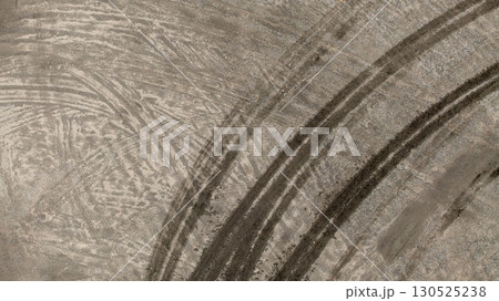 Aerial top view tire track on dirt sand mud, Texture of wet mud road with puddle and Tyre or tire track in countryside, Wheel tyre or tire track on mud, texture and background. Aerial top view tire track on dirt sand mud, Texture of wet mud road with puddle and Tyre or tire track in countryside, Wheel tyre or tire track on mud, texture and background. 130525238