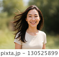 風に髪がなびく笑顔の若い女性 130525899