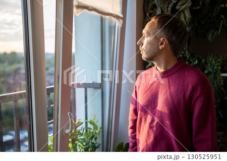 Thoughtful melancholic man gazing out kitchen window alone. Sad depressed male waiting at home Thoughtful melancholic man gazing out kitchen window alone. Sad depressed male waiting at home 130525951