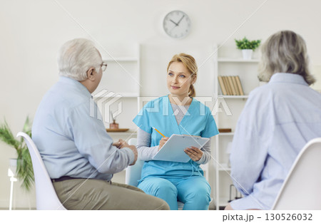 A doctor listens to an elderly couple sitting opposite, close-up 130526032