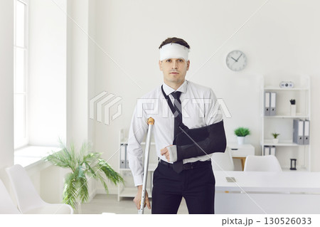 Injured male employee after accident with crutch and arm bandage. 130526033
