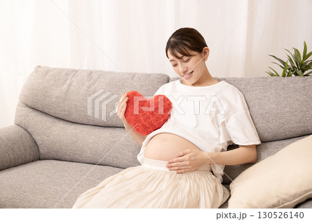 ソファーに座って赤いハートを持つ妊娠8ヶ月の女性 130526140