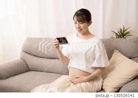 ソファーに座ってエコー写真を持つ妊婦の女性 ソファーに座ってエコー写真を持つ妊婦の女性 130526141