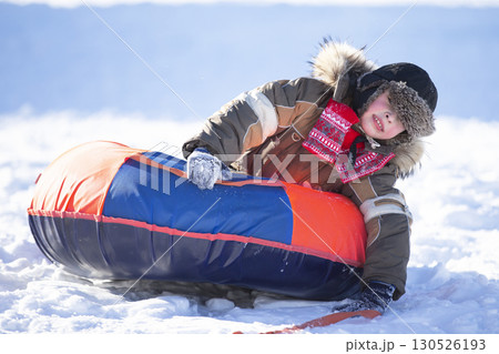 Happy little boy sledding on a snow slide. Child in winter. 130526193