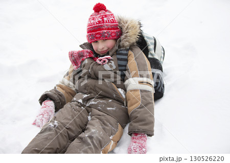 Funny boy in winter goes to school with a backpack.A little boy with a schoolbag sits in a snowdrift. Funny boy in winter goes to school with a backpack.A little boy with a schoolbag sits in a snowdrift. 130526220
