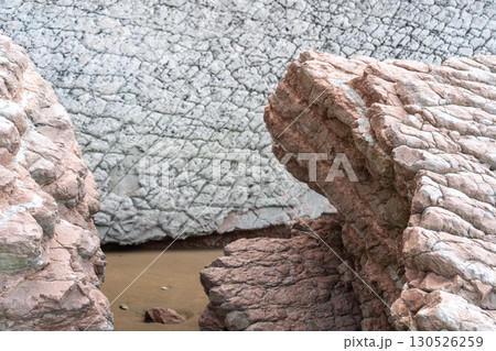The cold Atlantic Ocean is surrounded by cinematic layered rocks that look like a dragon The cold Atlantic Ocean is surrounded by cinematic layered rocks that look like a dragon 130526259