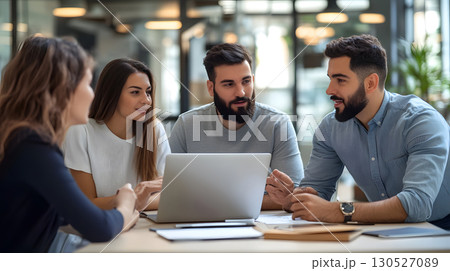 Group of professionals working together in an office, collaborating around a laptop during a team meeting. Great for teamwork, startup, and corporate use. 130527089