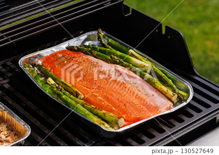 Grilled salmon fillets and asparagus sizzling on a barbecue grill Grilled salmon fillets and asparagus sizzling on a barbecue grill 130527649