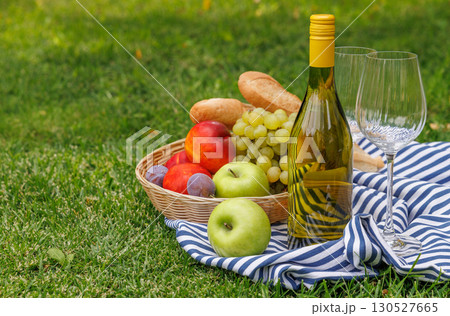 Picnic with wine, fruits, and baguette on a green meadow Picnic with wine, fruits, and baguette on a green meadow 130527665