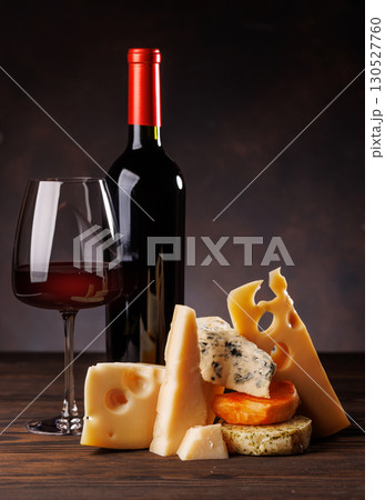 Assorted cheeses paired with glass of wine on a rustic table 130527760