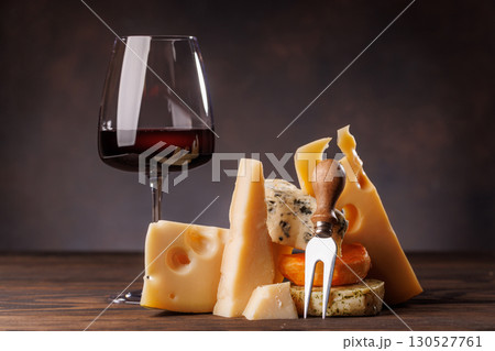 Assorted cheeses paired with glass of wine on a rustic table 130527761