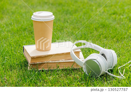Books, coffee, and headphones on a sunny lawn Books, coffee, and headphones on a sunny lawn 130527787