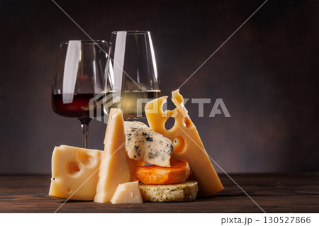 Assorted cheeses paired with glasses of wine on a rustic table 130527866