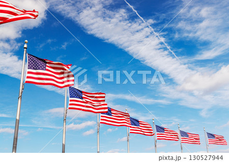 Rows of American flags waving against a sunny sky 130527944