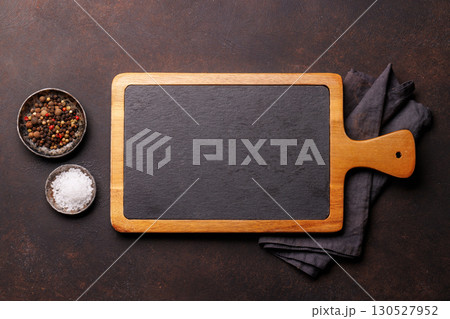 Empty stone cutting board with various spices on a rustic table 130527952