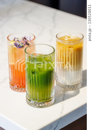 Assorted summer lemonades in glass jars with fresh fruits, ice, and garnishes 130528011