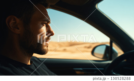 Young man driving a modern car through a desert landscape, enjoying the journey and the scenic view 130528288