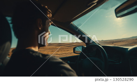 Young male navigating sleek vehicle across arid terrain during sunlit cross-country journey 130528290
