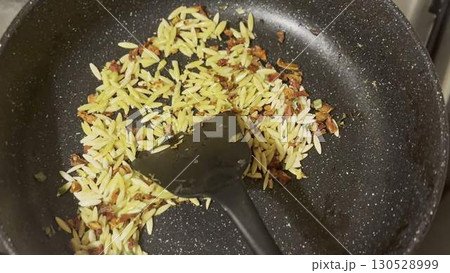 Cooking delicious orzo in a frying pan, close-up. Cooking delicious orzo in a frying pan, close-up. 130528999