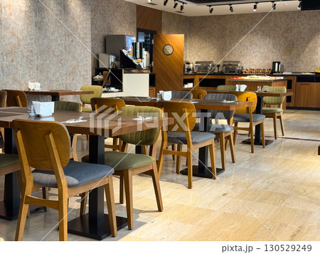 Dining hall with wooden tables and chairs arranged neatly in a modern interior. Hospitality, dining culture, and organized service environment in everyday lifestyle. 130529249