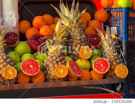 Fresh pineapples, pomegranates, oranges, and grapefruits on a street stall. Natural abundance, nutrition, and colorful presentation of fruit in everyday trade. 130529266