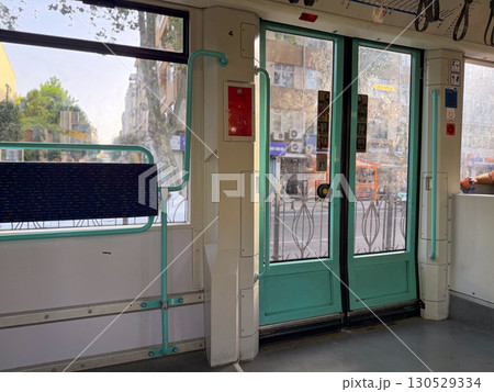 Inside of a tram with closed doors and view of the street outside. Public transport, travel, and daily commuting in the city. 130529334
