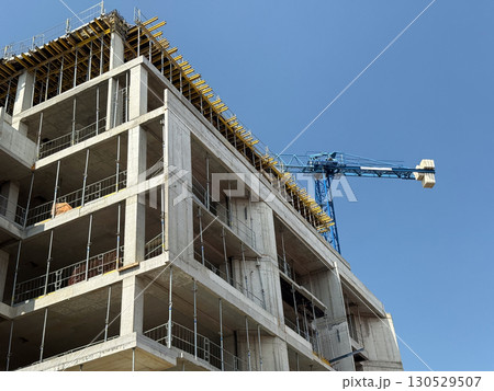 Brick walls and scaffolding at a construction site with a crane above. Architectural growth, structural engineering and urban expansion. Brick walls and scaffolding at a construction site with a crane above. Architectural growth, structural engineering and urban expansion. 130529507