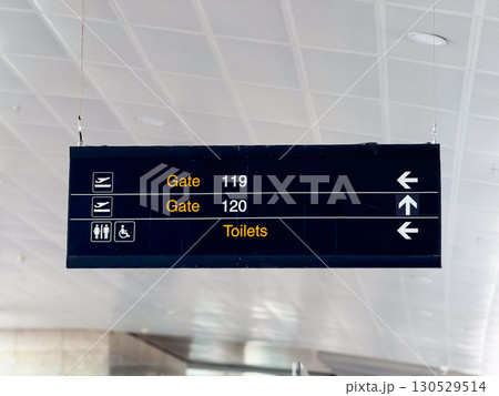 Airport directional sign with gates information in terminal hall. Travel navigation, passenger guidance, and public facility signage for aviation infrastructure. Airport directional sign with gates information in terminal hall. Travel navigation, passenger guidance, and public facility signage for aviation infrastructure. 130529514