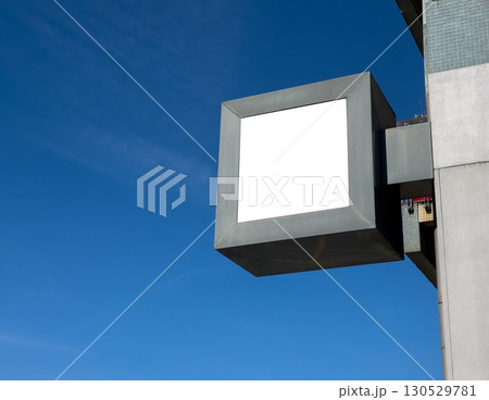 Empty square shop sign mockup mounted on store building with clear blue sky in the background. Empty square shop sign mockup mounted on store building with clear blue sky in the background. 130529781