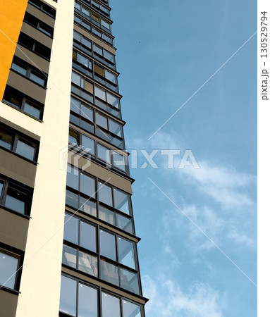 Low angle view of a tall modern apartment building with large reflective windows and a clean 130529794