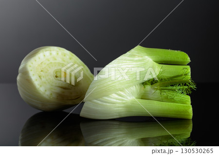 Cut fennel bulb with green stalks on a black background. Cut fennel bulb with green stalks on a black background. 130530265