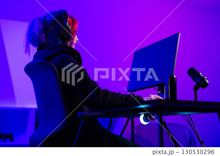 Young female gamer streaming a live session in a vibrant room setting 130530296