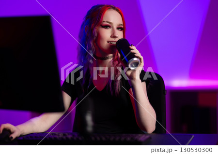 Young woman gaming and streaming in a vibrant room with neon lighting 130530300