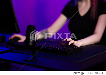 Young female gamer using a keyboard and mouse in a gaming setup 130530301