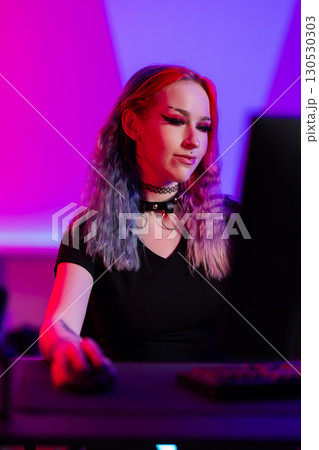Young woman gaming in vibrant pink and blue ambient lighting setting 130530303