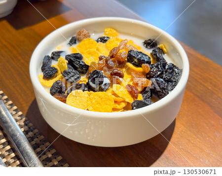 Bowl with cornflakes, raisins, and milk served for breakfast. Nutrition, daily habit, and food culture in lifestyle environment. 130530671